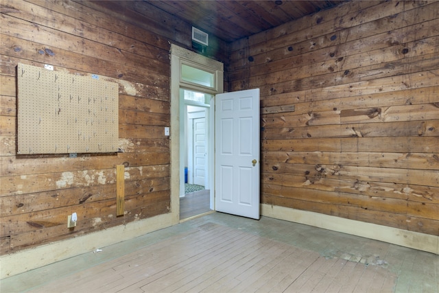 empty room featuring wood-type flooring, wooden walls, and wood ceiling