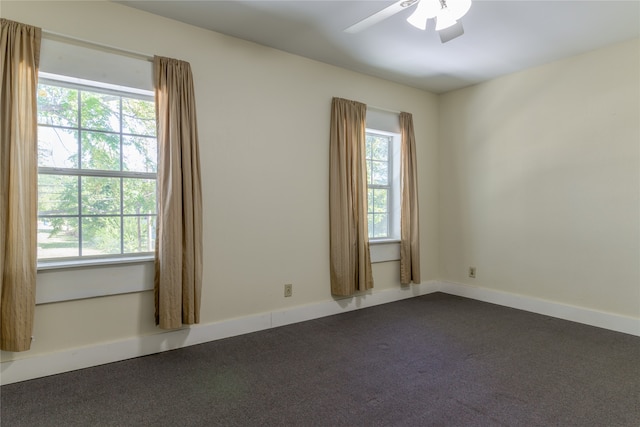 unfurnished room with dark colored carpet and ceiling fan