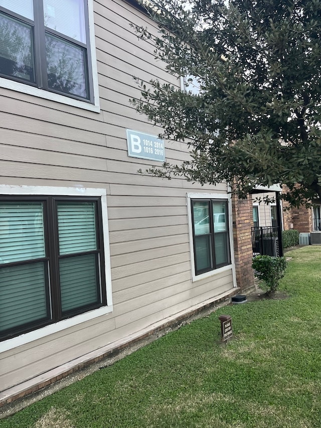 view of side of home with a yard and central AC