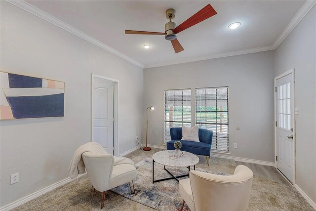 living area with ceiling fan, light colored carpet, and ornamental molding