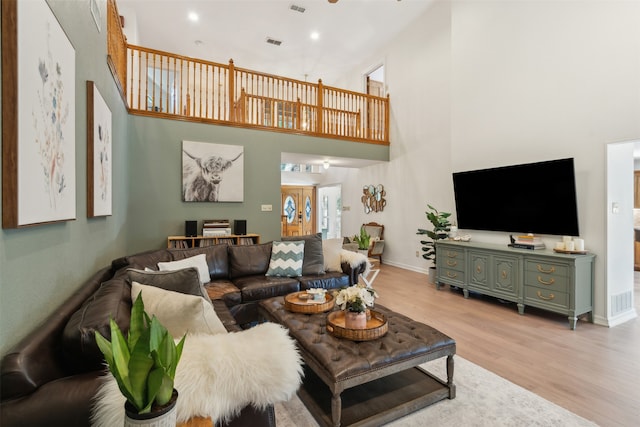 living room featuring light hardwood / wood-style flooring and a towering ceiling