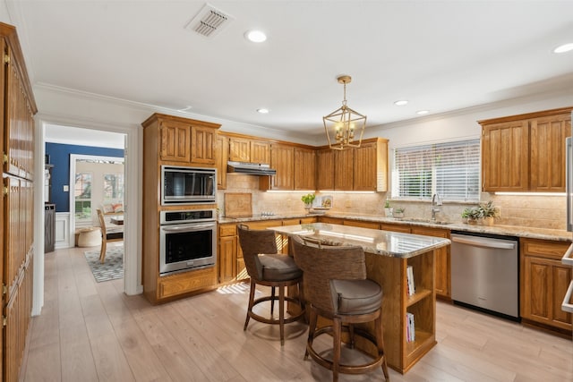 kitchen featuring pendant lighting, a wealth of natural light, a kitchen island, and appliances with stainless steel finishes