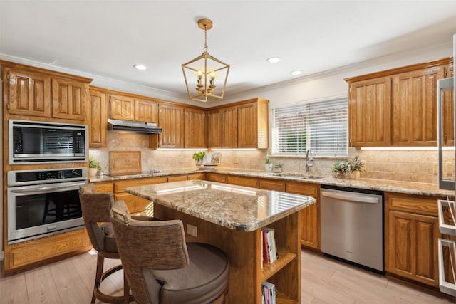 kitchen featuring sink, a center island, stainless steel appliances, light hardwood / wood-style flooring, and a notable chandelier