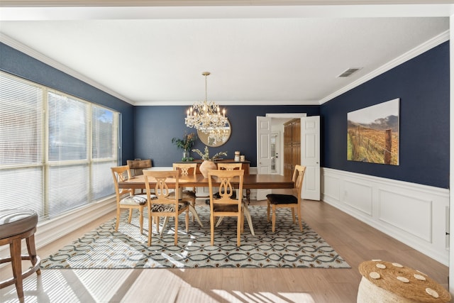 dining room featuring hardwood / wood-style flooring, a healthy amount of sunlight, crown molding, and a chandelier