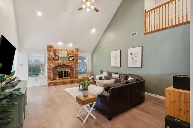 living room with a fireplace, light wood-type flooring, high vaulted ceiling, and ceiling fan