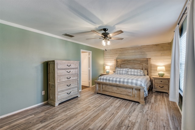 bedroom with ceiling fan, light hardwood / wood-style flooring, crown molding, and wooden walls