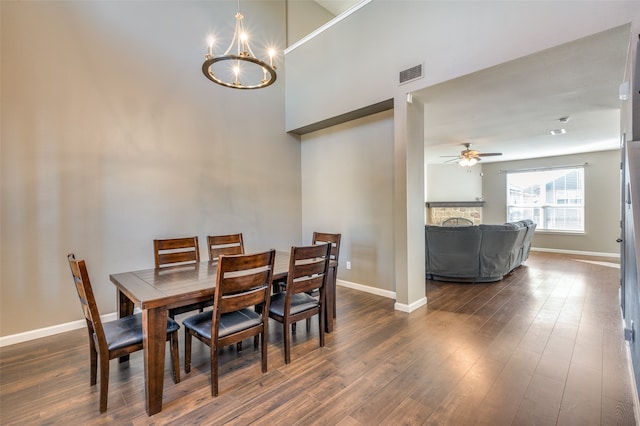 dining space featuring ceiling fan with notable chandelier and dark hardwood / wood-style flooring