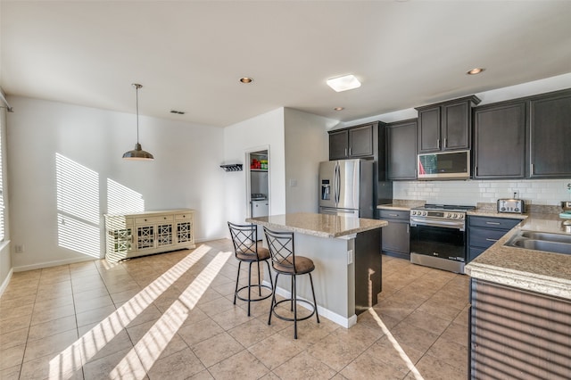 kitchen with decorative backsplash, appliances with stainless steel finishes, sink, pendant lighting, and a kitchen island