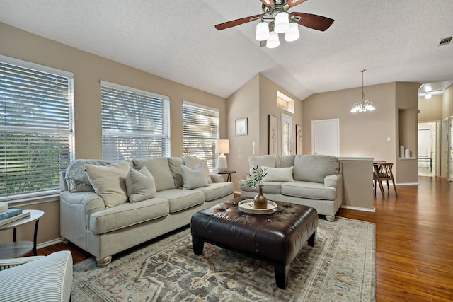 living room with ceiling fan with notable chandelier, lofted ceiling, dark wood-type flooring, and a wealth of natural light