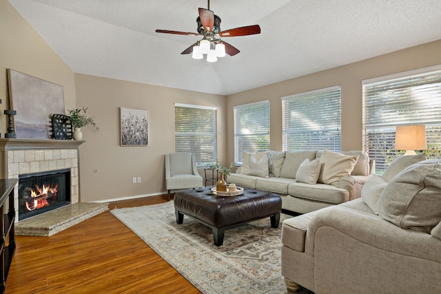 living room featuring a textured ceiling, ceiling fan, wood-type flooring, and vaulted ceiling