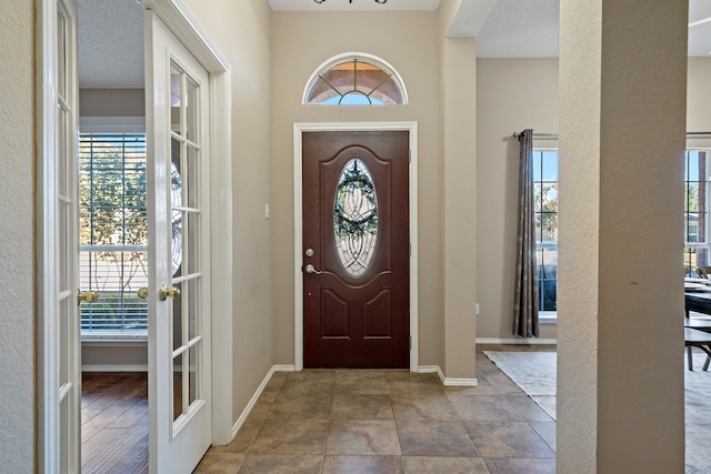 entrance foyer with french doors, a textured ceiling, and plenty of natural light