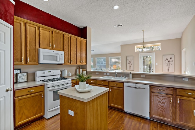 kitchen with a chandelier, dark hardwood / wood-style flooring, white appliances, and a center island