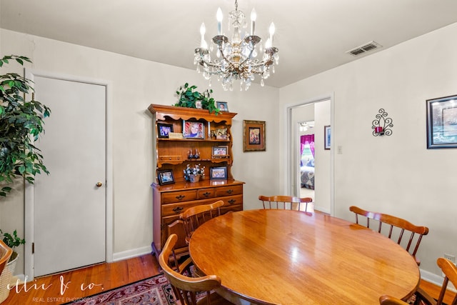 dining room with hardwood / wood-style floors and a chandelier