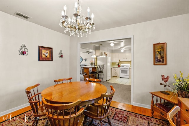 dining room with ceiling fan with notable chandelier and light hardwood / wood-style floors