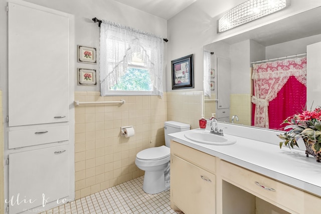 bathroom featuring tile patterned flooring, vanity, toilet, and tile walls