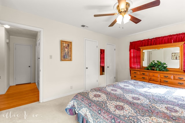 bedroom with ceiling fan, two closets, and light wood-type flooring