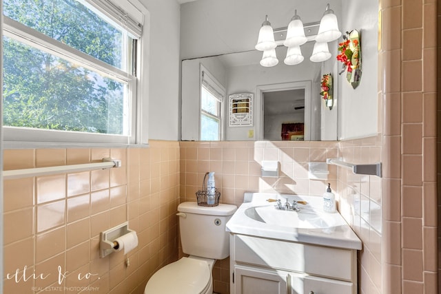 bathroom featuring vanity, toilet, and tile walls