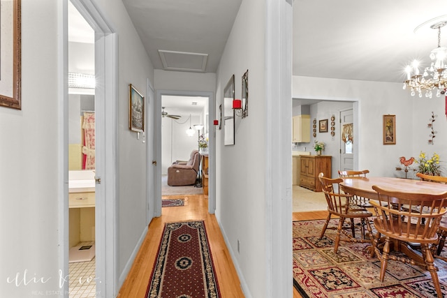 corridor with light hardwood / wood-style floors and a notable chandelier