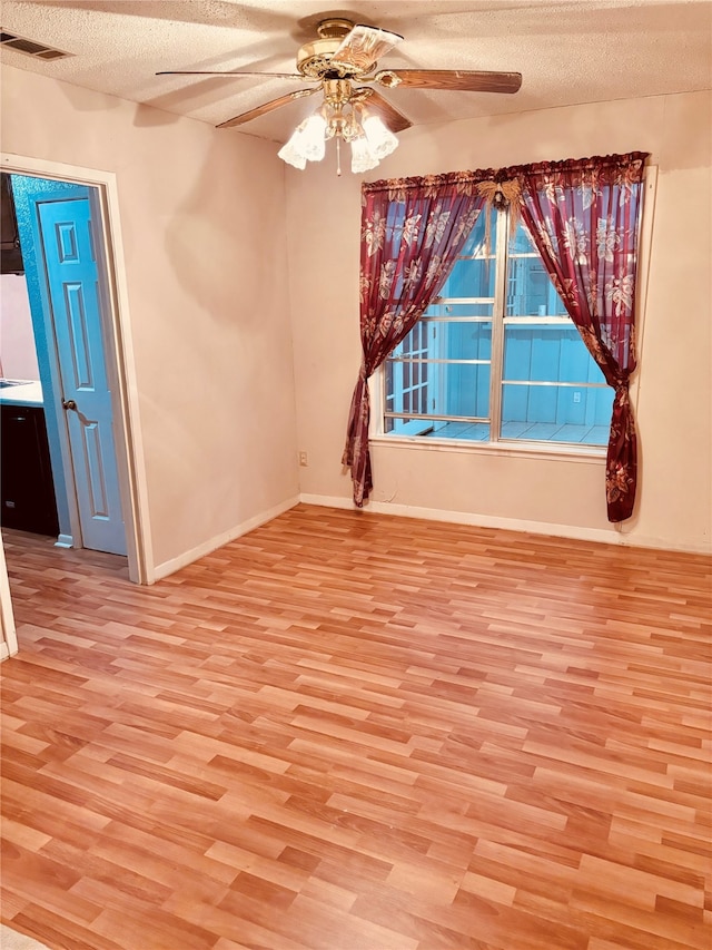 empty room with ceiling fan, light hardwood / wood-style floors, and a textured ceiling