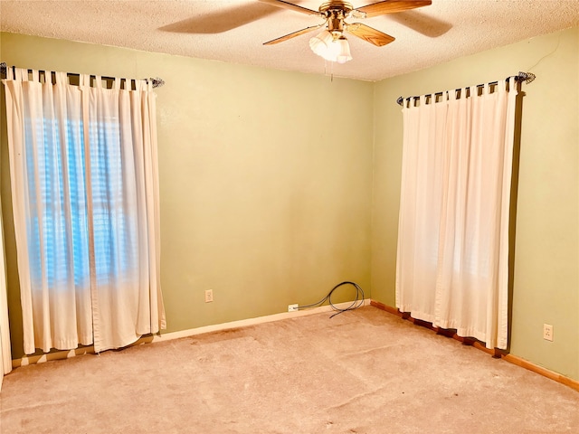 carpeted spare room with a textured ceiling, ceiling fan, and a healthy amount of sunlight