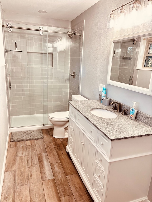 bathroom featuring hardwood / wood-style floors, vanity, toilet, and walk in shower