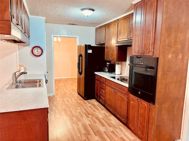 kitchen featuring sink, light hardwood / wood-style flooring, crown molding, a textured ceiling, and black appliances