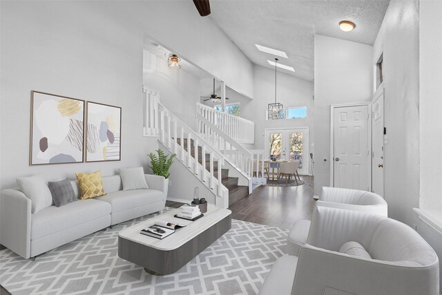 living room featuring hardwood / wood-style floors, high vaulted ceiling, french doors, ceiling fan, and a textured ceiling