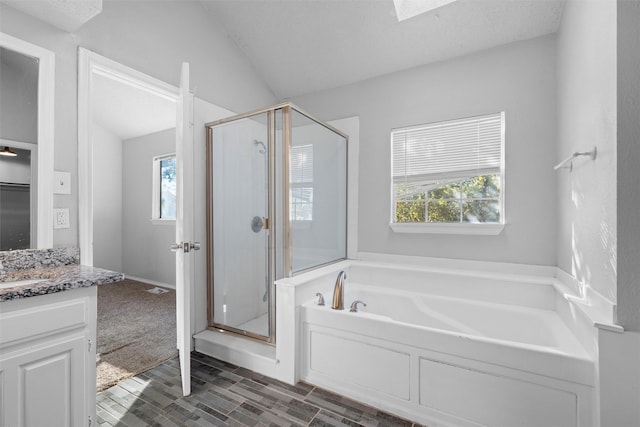 bathroom with plus walk in shower, a textured ceiling, vanity, and lofted ceiling with skylight