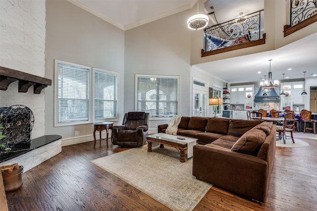 living room featuring a high ceiling, dark hardwood / wood-style floors, ornamental molding, and a notable chandelier