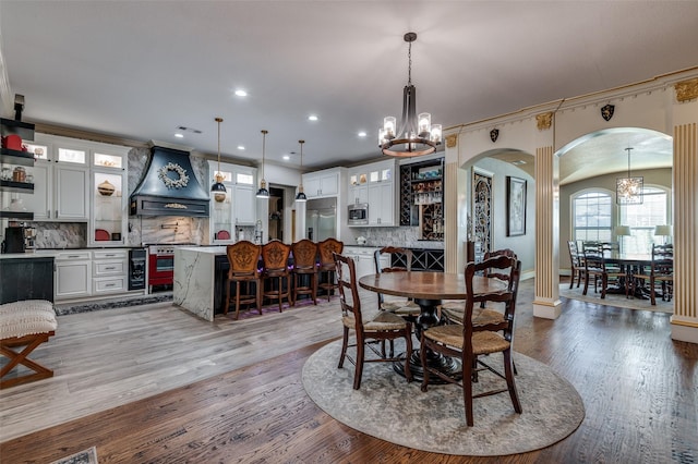 dining space with light wood-type flooring, an inviting chandelier, and crown molding