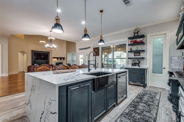 kitchen featuring light wood-type flooring, light stone counters, a kitchen island with sink, pendant lighting, and dishwasher