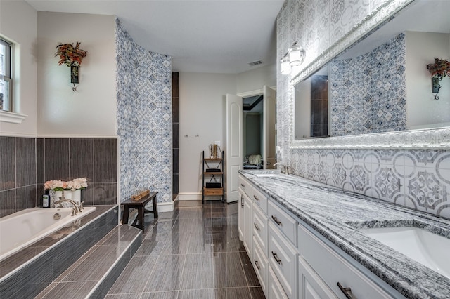 bathroom with tile patterned flooring, vanity, a bathtub, and tile walls