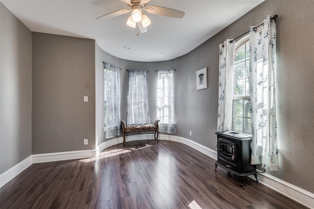 unfurnished room with hardwood / wood-style flooring, a wood stove, and ceiling fan