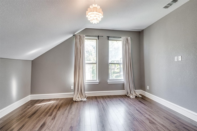 bonus room featuring hardwood / wood-style floors, a healthy amount of sunlight, lofted ceiling, and a textured ceiling