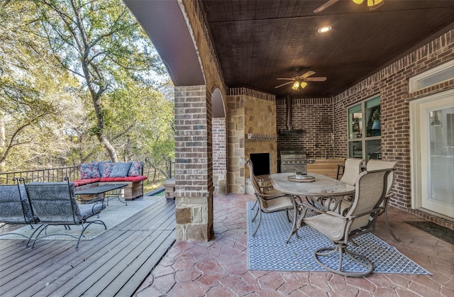 view of patio / terrace featuring an outdoor living space with a fireplace, area for grilling, ceiling fan, and a deck