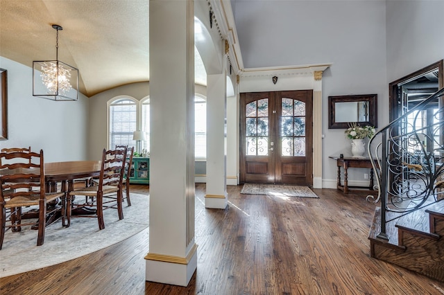 foyer entrance with french doors, dark hardwood / wood-style flooring, an inviting chandelier, and vaulted ceiling