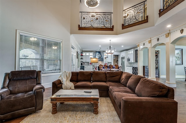 living room featuring plenty of natural light, light wood-type flooring, a towering ceiling, and a chandelier