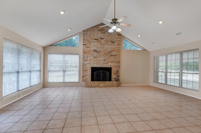 unfurnished living room featuring a fireplace, light tile patterned floors, high vaulted ceiling, and plenty of natural light