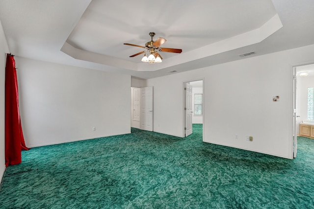 empty room featuring a raised ceiling and carpet floors