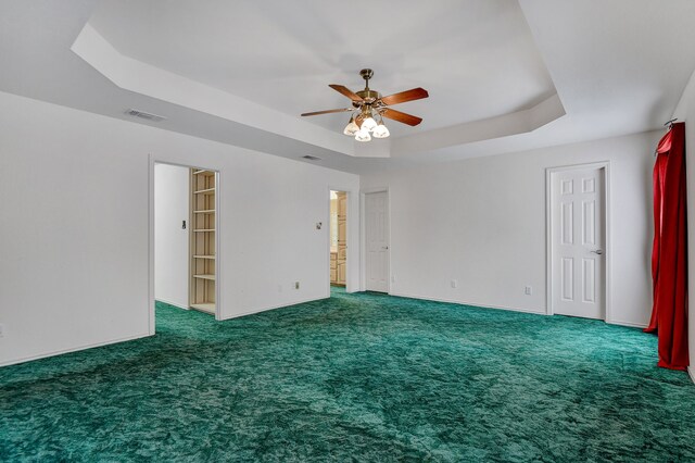 carpeted spare room featuring a raised ceiling and ceiling fan