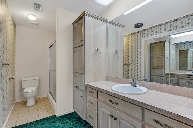 bathroom with tile patterned flooring, vanity, toilet, and a shower with door