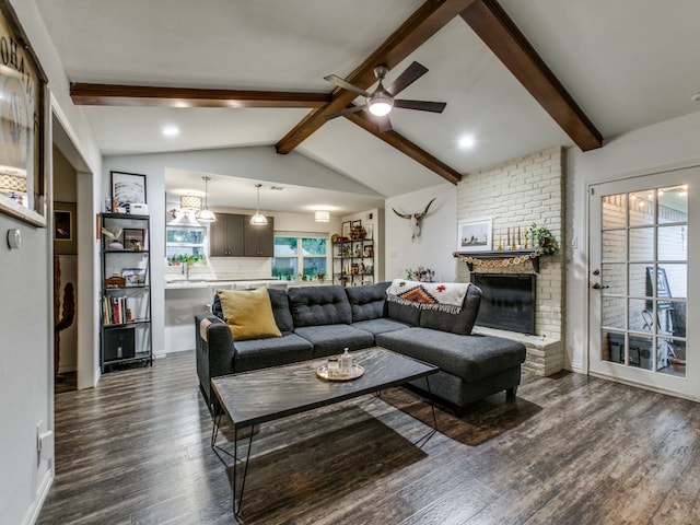 living room featuring dark hardwood / wood-style floors, lofted ceiling with beams, a fireplace, and a wealth of natural light