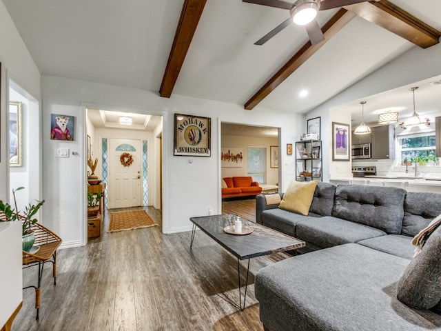 living room featuring hardwood / wood-style floors, vaulted ceiling with beams, ceiling fan, and sink