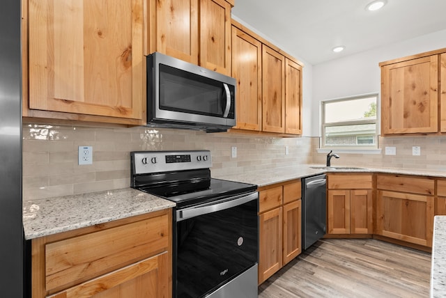 kitchen with sink, stainless steel appliances, tasteful backsplash, and light hardwood / wood-style flooring