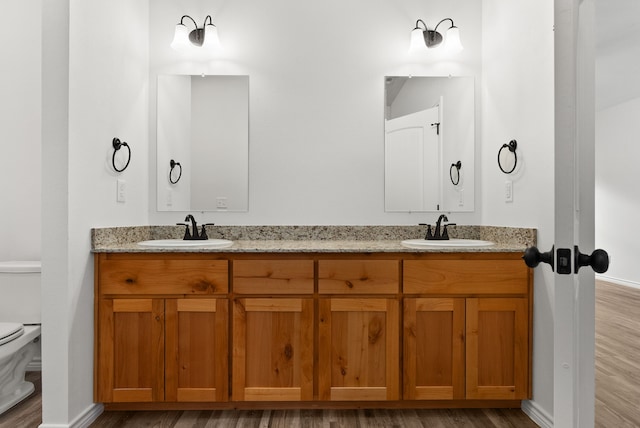 bathroom with wood-type flooring, vanity, and toilet