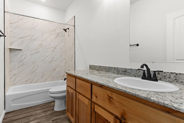 full bathroom with hardwood / wood-style floors, vanity, tiled shower / bath combo, and toilet