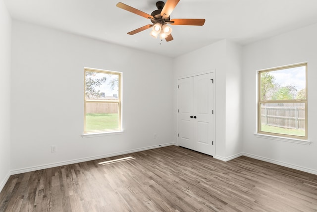 unfurnished bedroom featuring ceiling fan, a closet, light wood-type flooring, and multiple windows