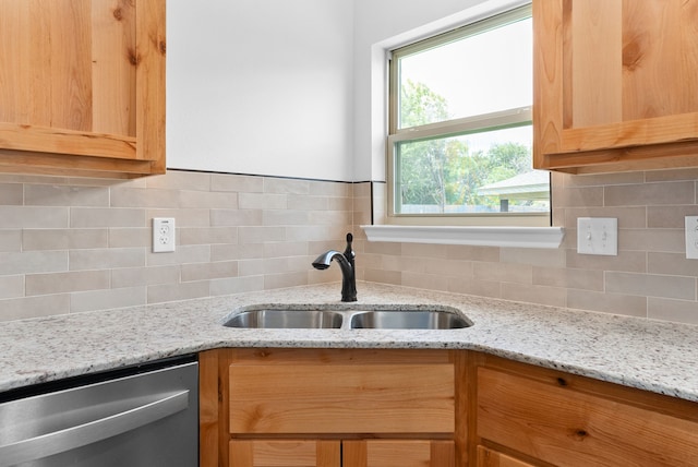 kitchen with decorative backsplash, light stone counters, stainless steel dishwasher, and sink