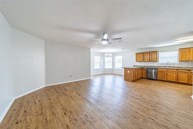 kitchen with stainless steel dishwasher, kitchen peninsula, sink, and light hardwood / wood-style flooring