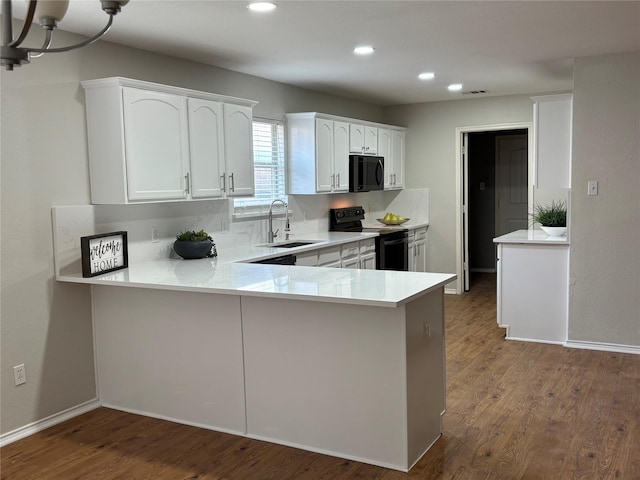 kitchen with dark hardwood / wood-style floors, black appliances, sink, white cabinets, and kitchen peninsula